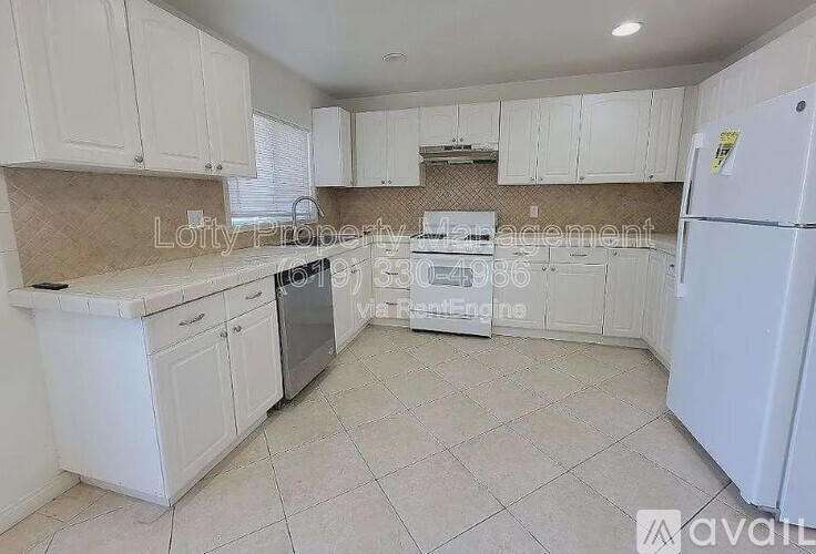 A kitchen with white cabinets and appliances is available for rent.