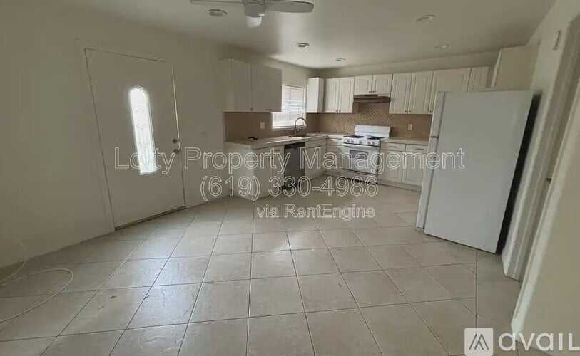 A spacious kitchen with white appliances and a tiled floor.