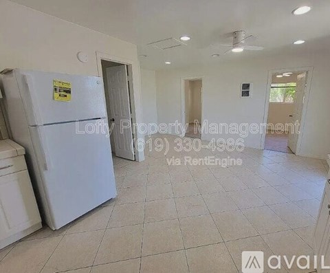 A white refrigerator is in a room with tiled flooring and white walls.