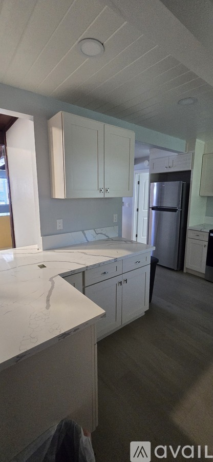 A kitchen with white cabinets and a marble countertop.