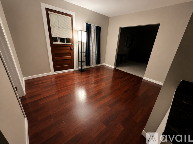 A room with wooden flooring and a door leading to another room.