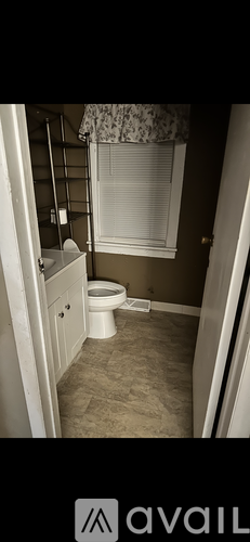 A small bathroom with a toilet and a window with blinds.
