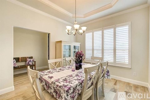 A dining room with a floral tablecloth and chairs.