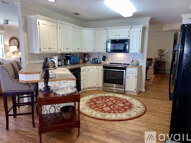 A kitchen with white cabinets and a wooden floor.