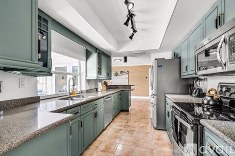 A kitchen with green cabinets and a tile floor.