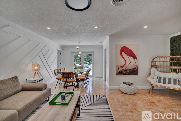 A living room with a sofa, a coffee table, and a painting of a flamingo.