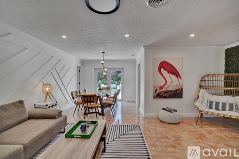 A living room with a sofa, a coffee table, and a painting of a flamingo.