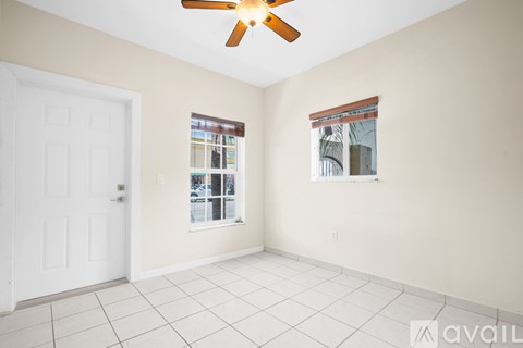 A room with a ceiling fan and two windows.