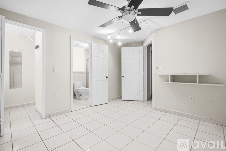 A spacious bathroom with a toilet, sink, and a fan.