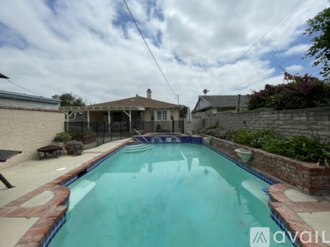 A pool surrounded by a brick wall and a patio area.