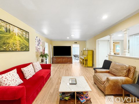 A living room with a red couch and a painting on the wall.