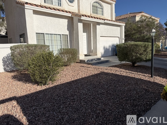 A house with a driveway and a hedge in front.