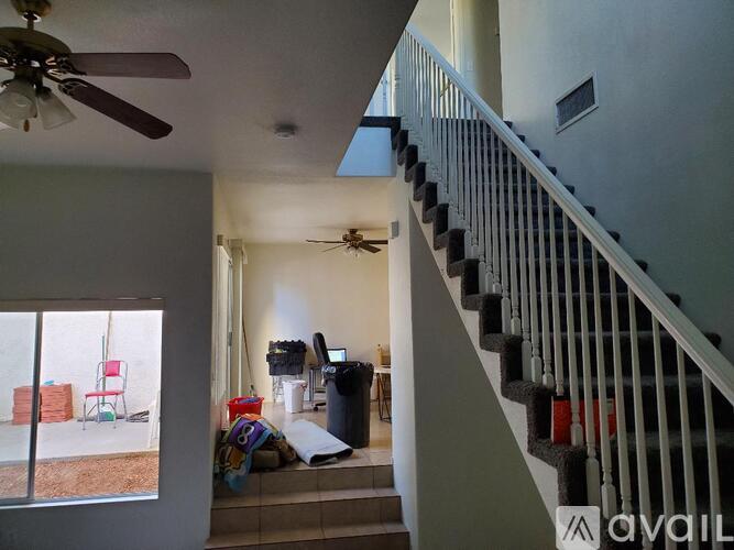A living room with a ceiling fan and a staircase.