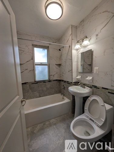 A bathroom with a marble wall and a tub, sink, and toilet.