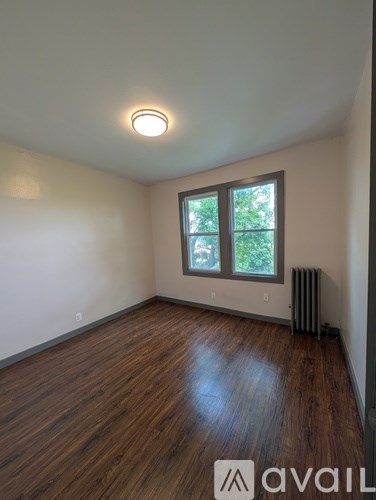 A room with wooden floors and a window with a view of trees.