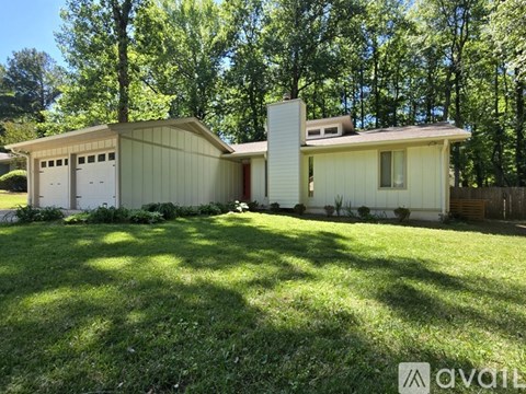 A house with a white garage door is surrounded by trees.