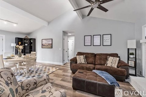 A living room with a brown couch and a ceiling fan.
