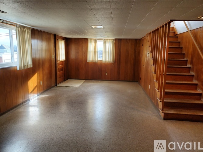 A spacious room with wooden walls and a staircase on the right side.