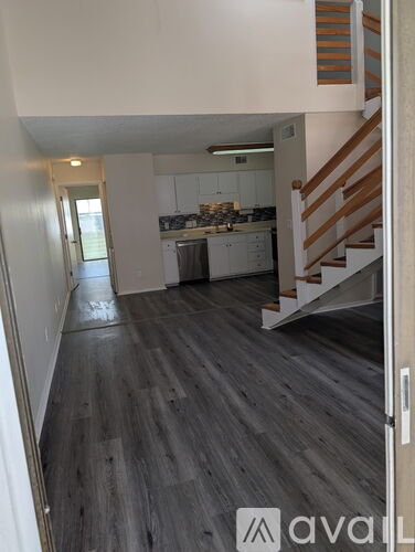 A hallway with a staircase leading to a kitchen.