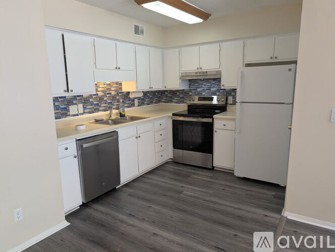A kitchen with white cabinets and a tiled backsplash.