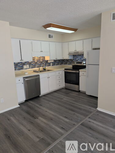 A kitchen with white cabinets and a wooden floor.