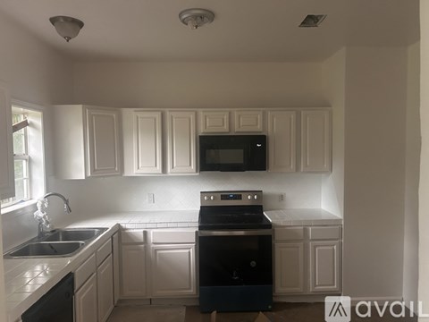 A kitchen with white cabinets and a black stove top oven.