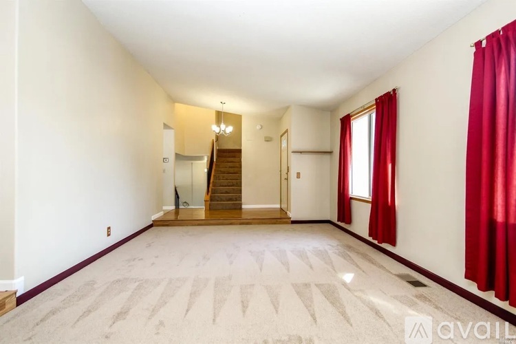 A spacious room with a staircase and red curtains.