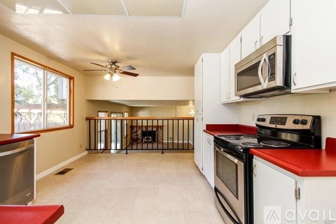 A kitchen with white cabinets and a red countertop.