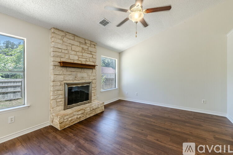 A room with a stone fireplace and a ceiling fan.
