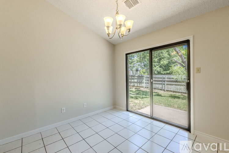 A large, empty room with wood flooring and a stone fireplace.