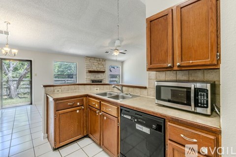 A kitchen with wooden cabinets and a black dishwasher.