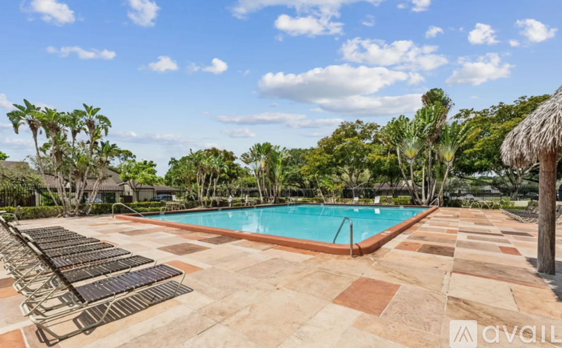A swimming pool surrounded by a tiled patio and lounge chairs.