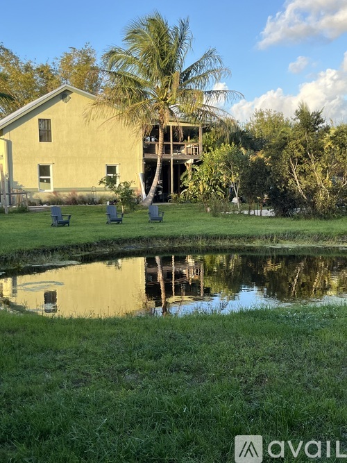 A house with a pool in front and a palm tree in the background.