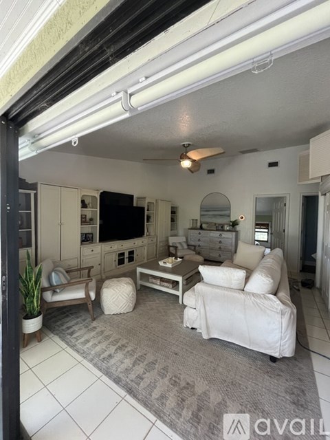 A living room with a white couch and a grey rug.