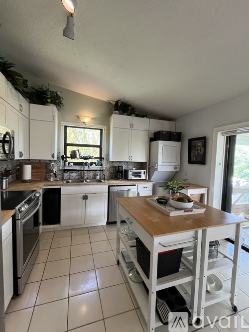 A kitchen with white cabinets and a wooden island.