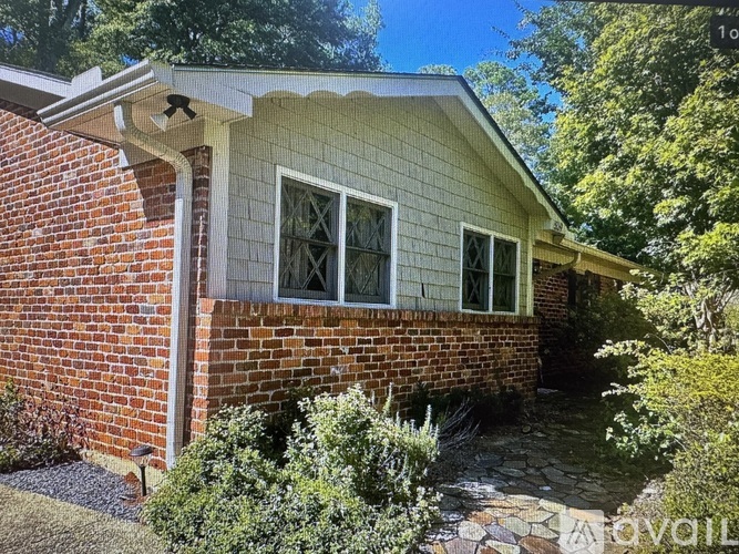 A small house with a red brick wall and a white window.