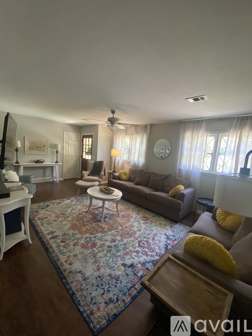 A living room with a rug, a sofa, a chair, and a table.