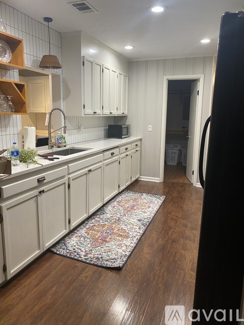 A kitchen with white cabinets and a wooden floor.