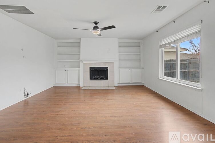 A spacious living room with a fireplace and a ceiling fan.