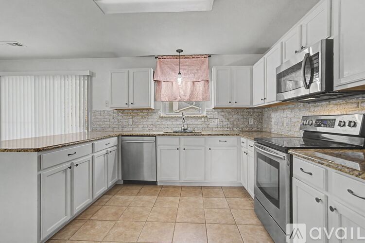 A kitchen with white cabinets and a marble backsplash.