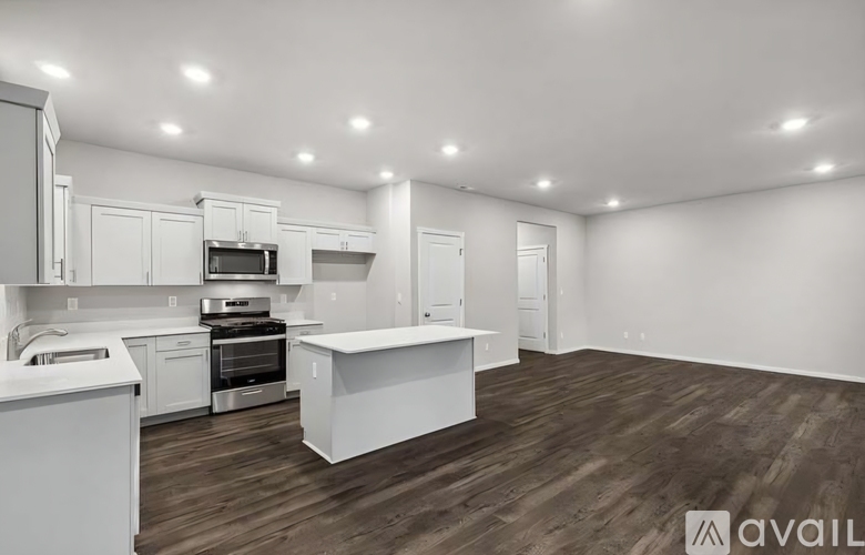 A modern kitchen with white cabinets and a wooden floor.