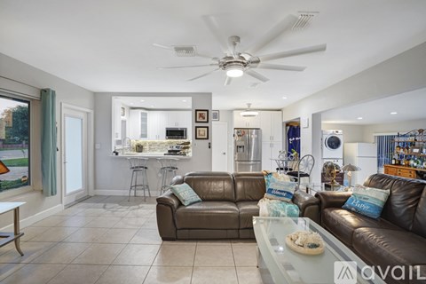 A living room with a brown couch and a ceiling fan.