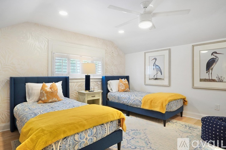 A bedroom with two beds and a ceiling fan.