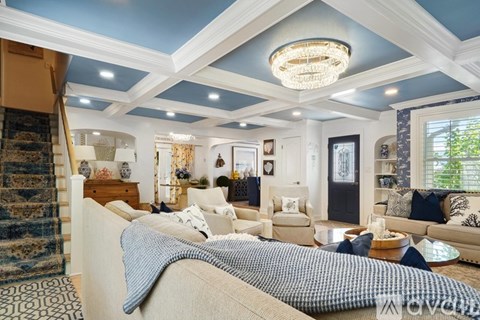 A living room with a beige sofa and a chandelier.