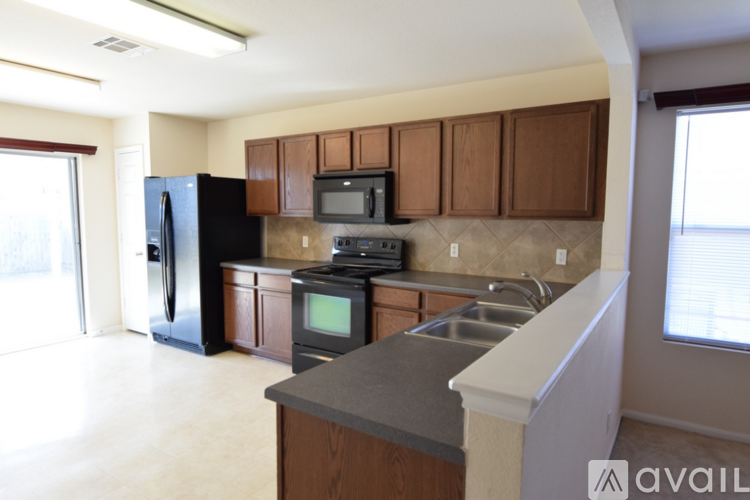 A kitchen with brown cabinets and a black refrigerator.