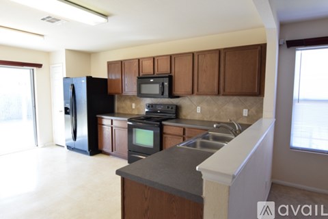A kitchen with brown cabinets and a black refrigerator.