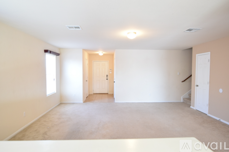 A spacious room with a door in the middle and a staircase on the right side.
