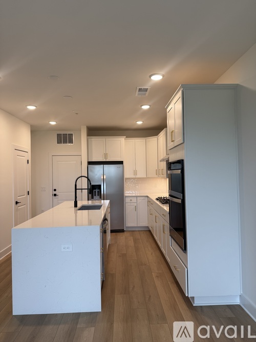 A modern kitchen with white cabinets and a wooden floor.