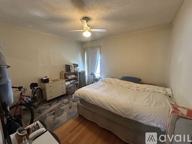 A bedroom with a bed, dresser, and bicycle.