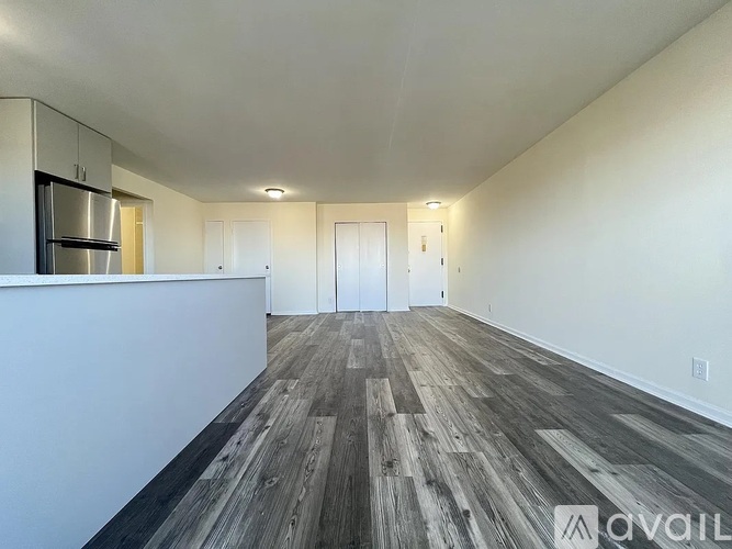 A spacious room with wood flooring and white walls.